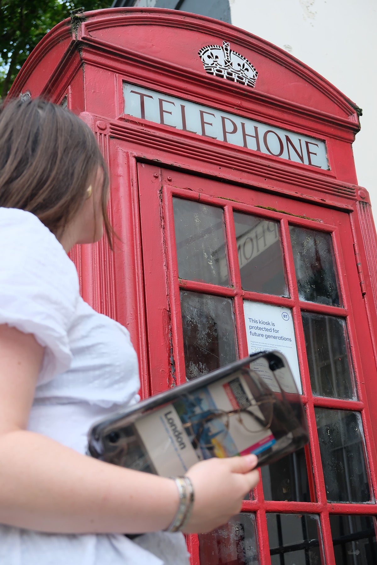 Customer holding a DivideNPac organizer with a London label in front of a red telephone box in London.